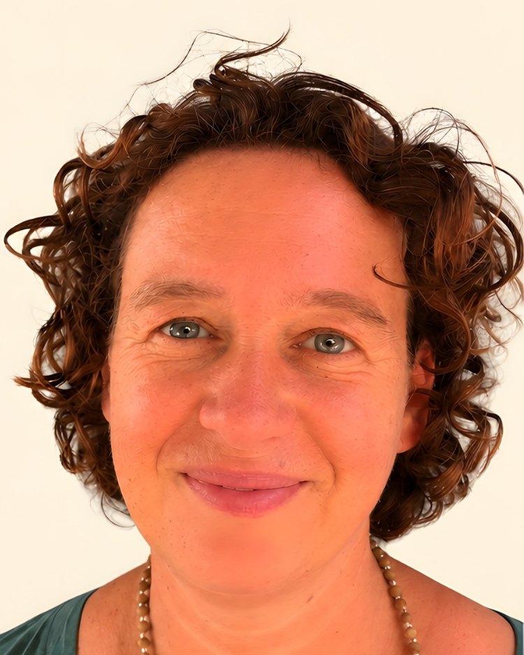 Porträt von Claudia Seifert: Frau mit dunklen Locken in einem grünen Oberteil.